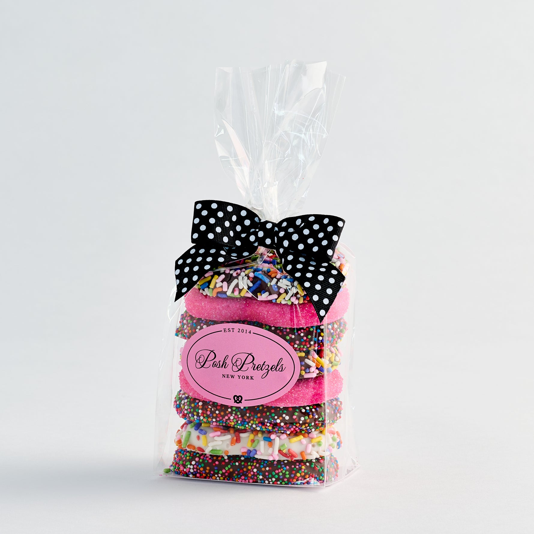 Bag of colorful sprinkles with a black and white polka dot bow on a light gray background